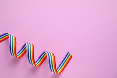 Photo of Bright rainbow ribbon on color background, top view with space for text. Symbol of gay community