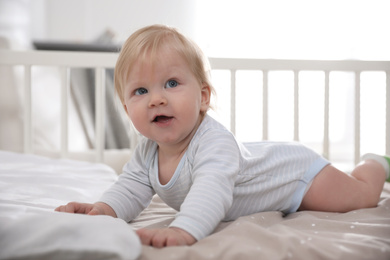 Photo of Adorable little baby lying in comfortable crib