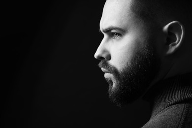 Portrait of handsome bearded man on dark background, space for text. Black and white effect