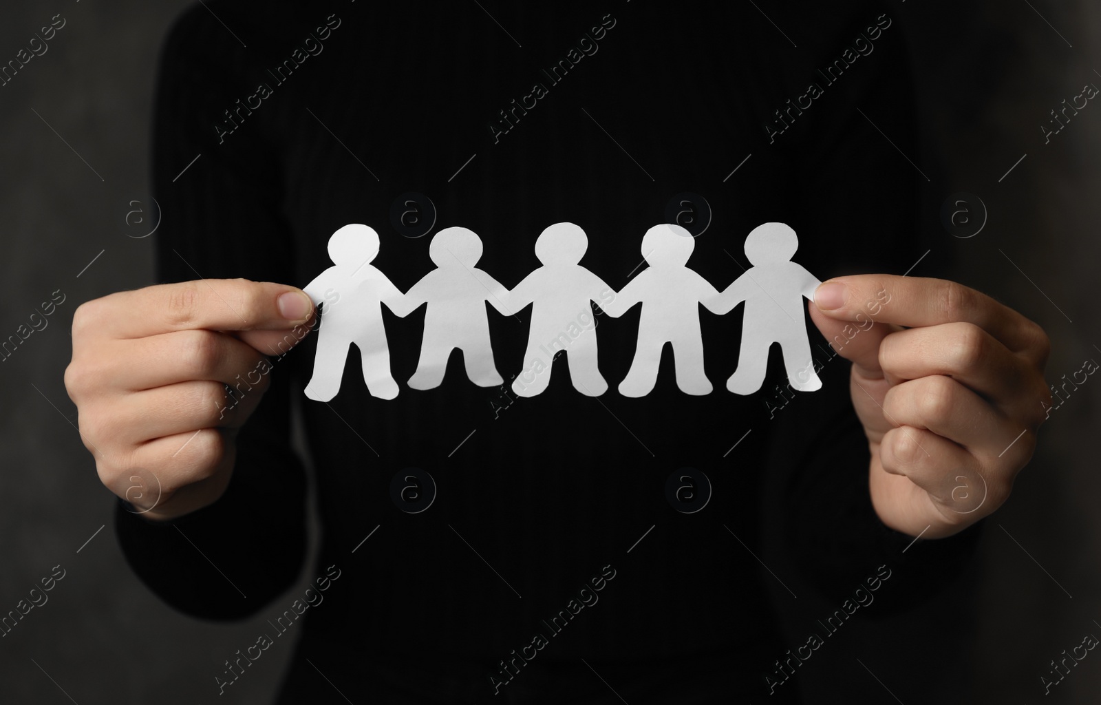 Photo of Woman holding paper people chain on grey background, closeup. Unity concept
