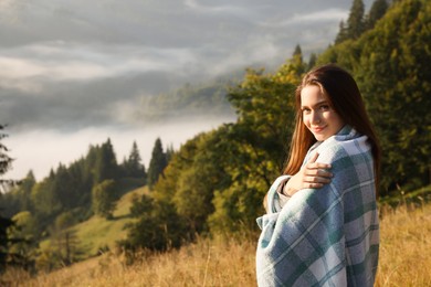 Photo of Woman with cozy plaid enjoying warm sunlight in nature
