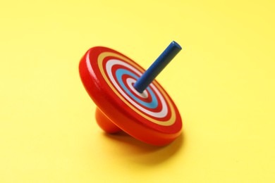Photo of One colorful spinning top on yellow background, closeup