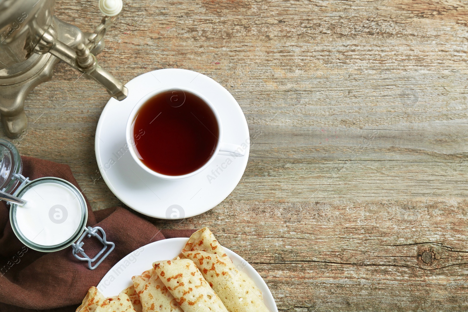 Photo of Vintage samovar, cup of hot drink and pancakes served on wooden table, flat lay with space for text. Traditional Russian tea ceremony