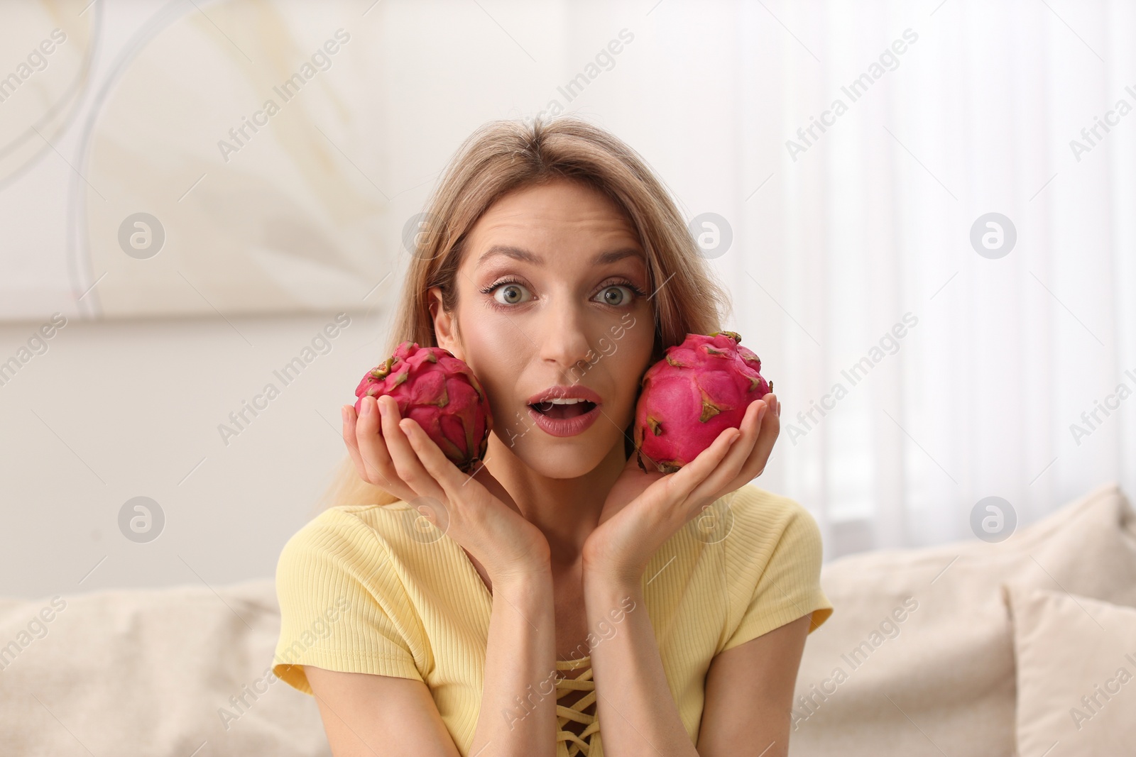 Photo of Young woman with fresh pitahayas at home. Exotic fruits