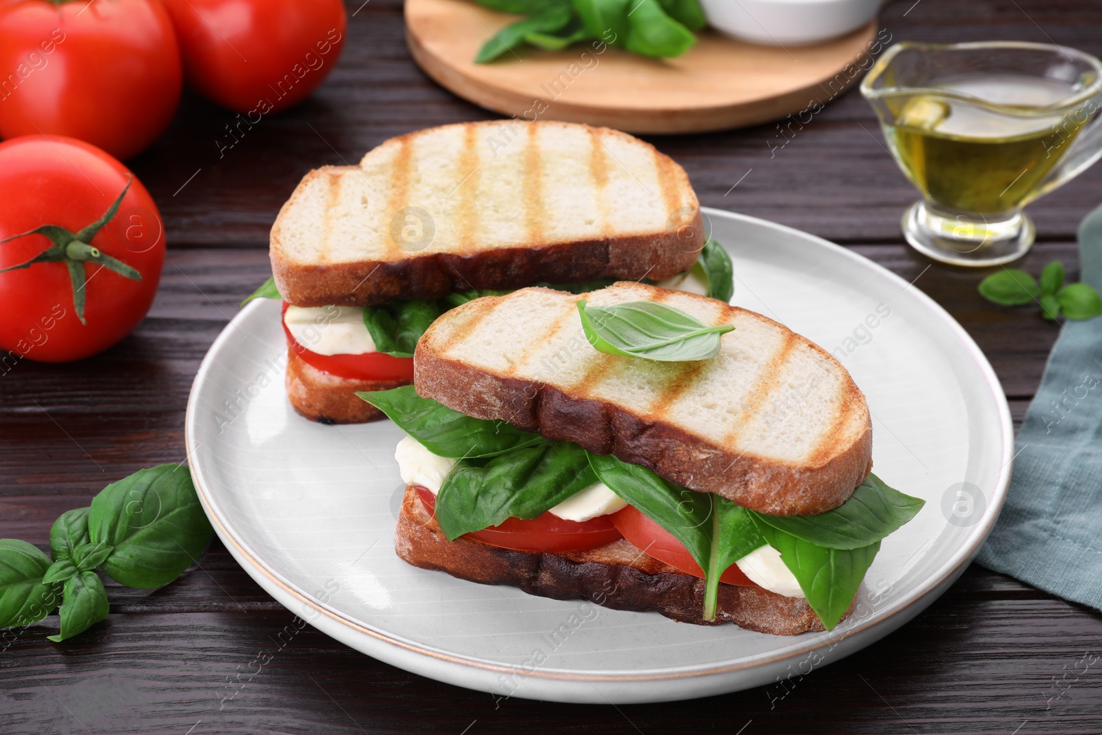 Photo of Delicious Caprese sandwiches with mozzarella, tomatoes and basil on wooden table