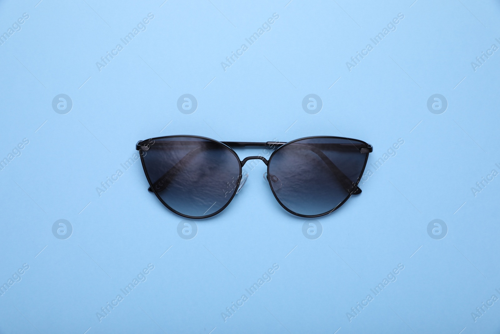 Photo of Stylish sunglasses on light blue background, top view