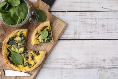 Photo of Delicious cut pie with spinach on white wooden table, top view. Space for text