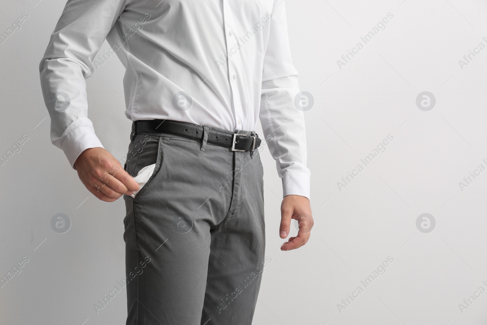 Photo of Businessman showing empty pocket on light background, closeup. Space for text