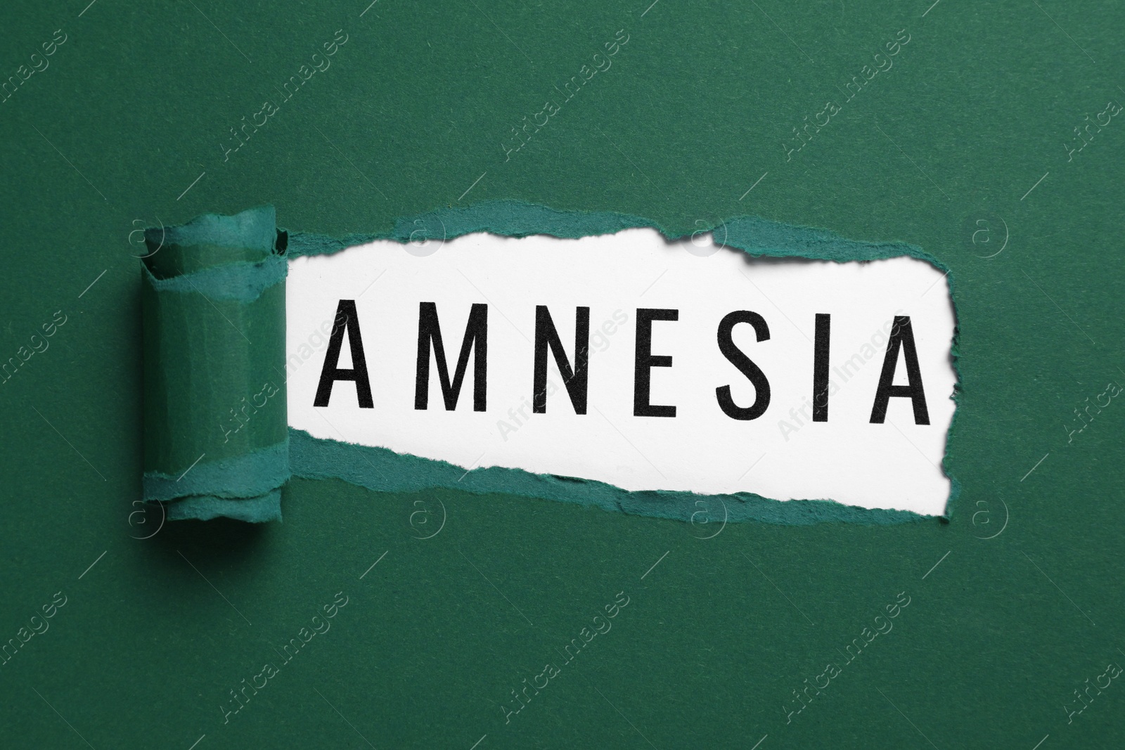 Photo of Word Amnesia on white background, view through hole in green paper