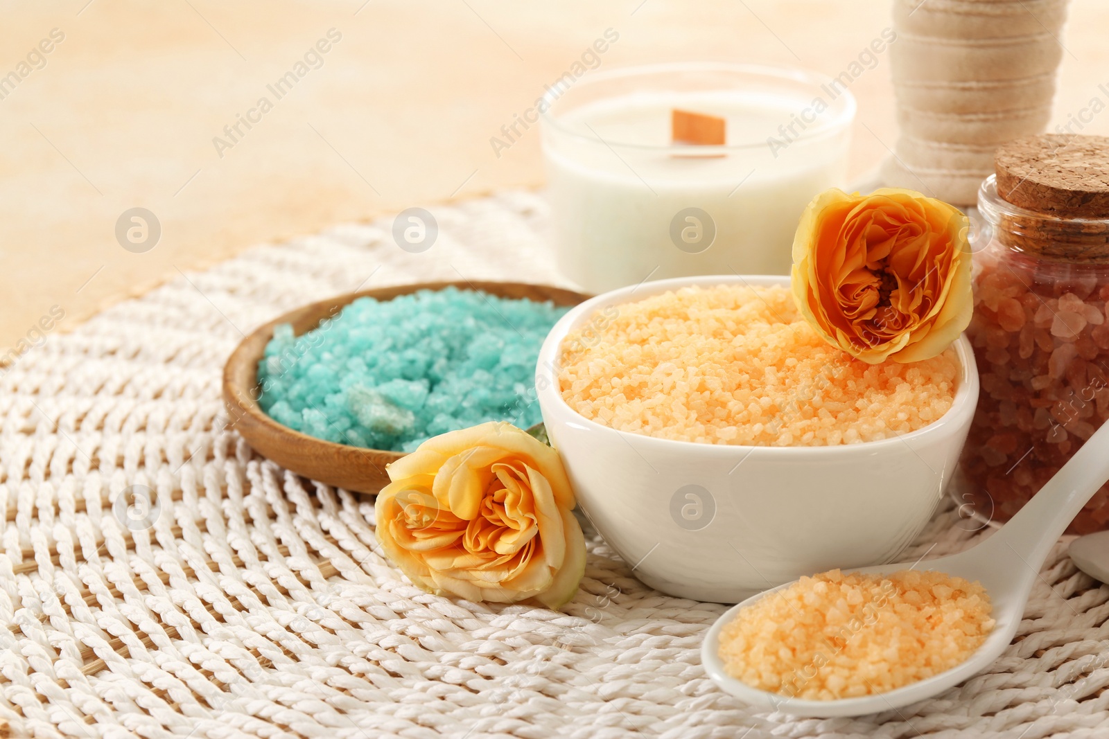 Photo of Aromatic sea salt and beautiful flowers on wicker mat. Space for text