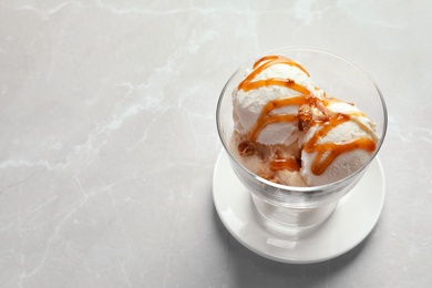 Bowl with caramel ice cream on light background