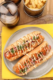 Photo of Delicious hot dogs with bacon, carrot and parsley served on wooden table, flat lay