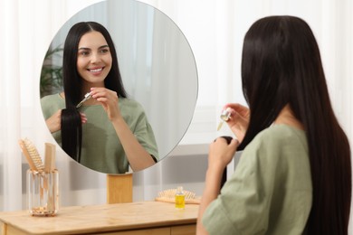 Photo of Beautiful woman applying hair serum in room. Cosmetic product