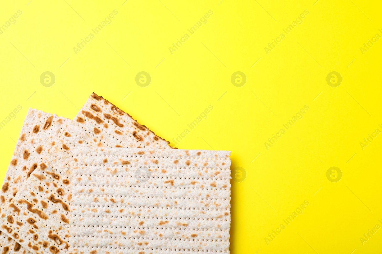 Photo of Traditional matzos on yellow background, flat lay. Space for text