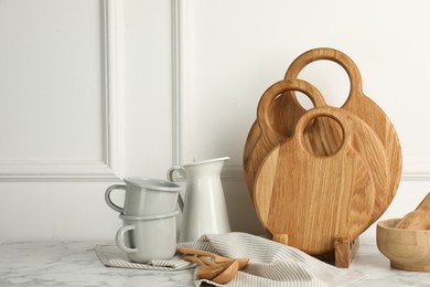 Photo of Wooden cutting boards, spoons and dishware on white marble table. Space for text