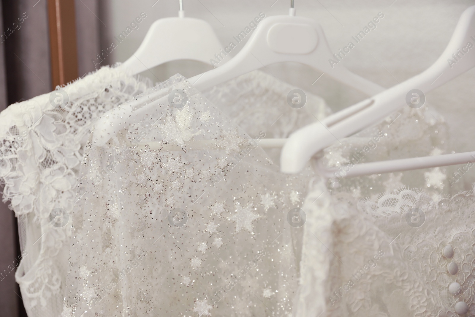 Photo of Beautiful wedding dresses hanging in boutique, closeup