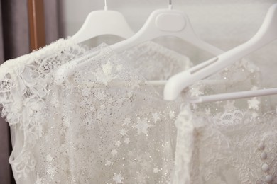 Photo of Beautiful wedding dresses hanging in boutique, closeup