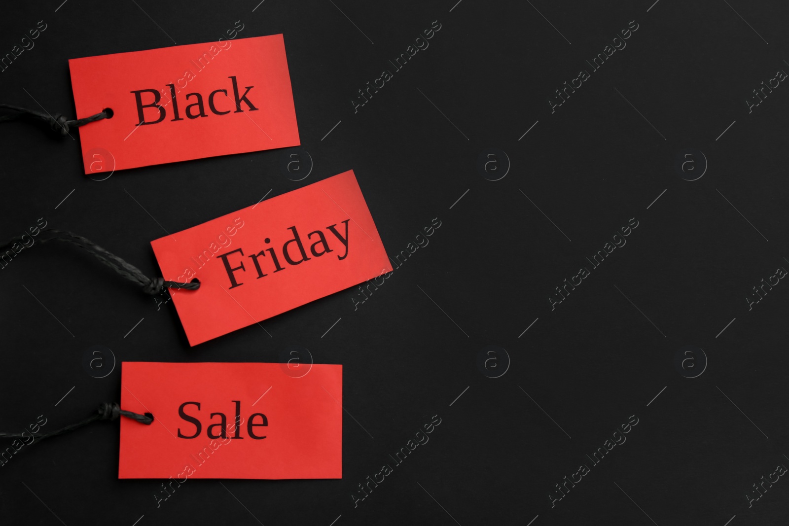 Photo of Red tags with words BLACK FRIDAY SALE on dark background, flat lay. Space for text