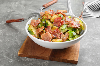 Photo of Delicious roasted Brussels sprouts with bacon served on grey table