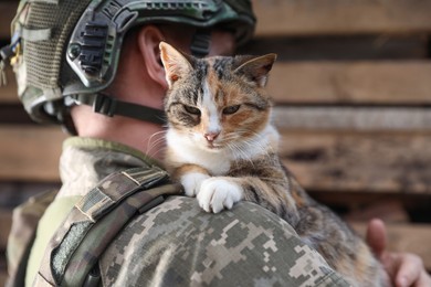 Photo of Ukrainian soldier rescuing stray cat outdoors, closeup