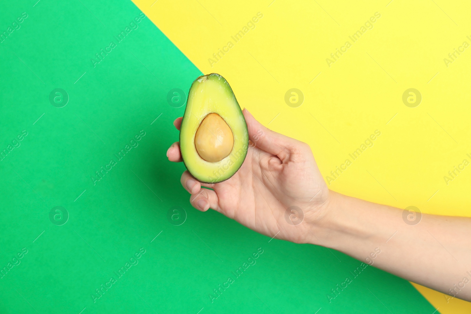 Photo of Woman holding ripe cut avocado on color background