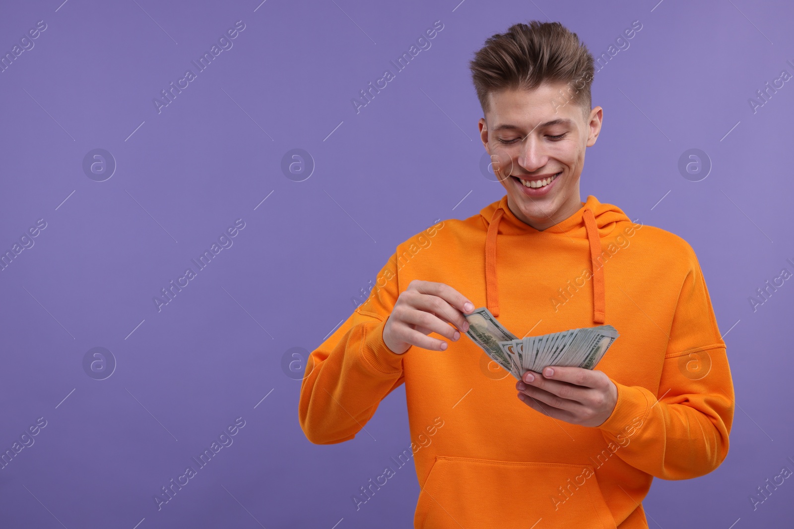 Photo of Happy man with money on purple background. Space for text