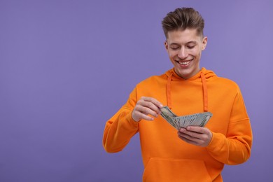 Photo of Happy man with money on purple background. Space for text