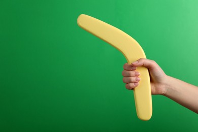 Photo of Woman holding boomerang on green background, closeup. Space for text
