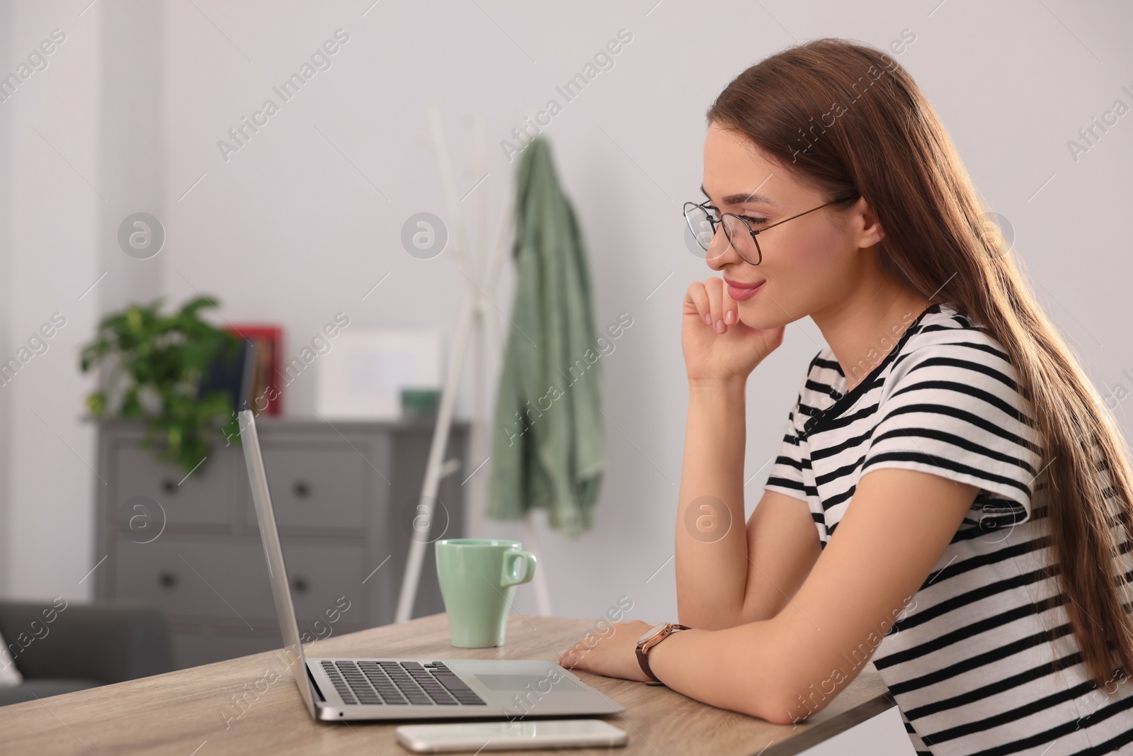 Photo of Happy young woman with laptop at table indoors