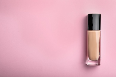 Photo of Bottle of skin foundation and space for text on color background, top view