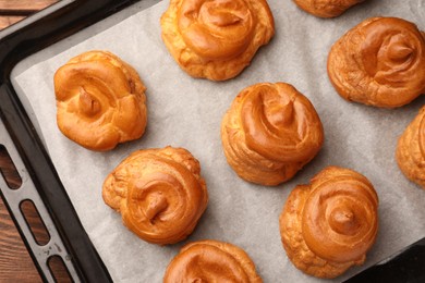 Delicious profiteroles on baking pan, top view