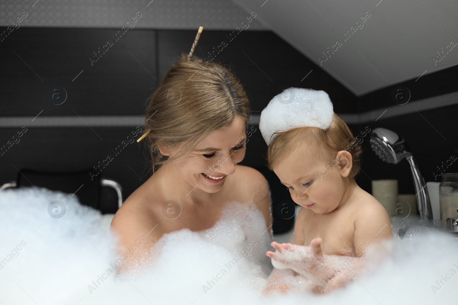 Photo of Mother with her child taking bubble bath together indoors