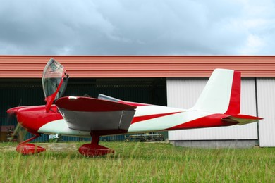 Ultralight airplane on green grass near hangar