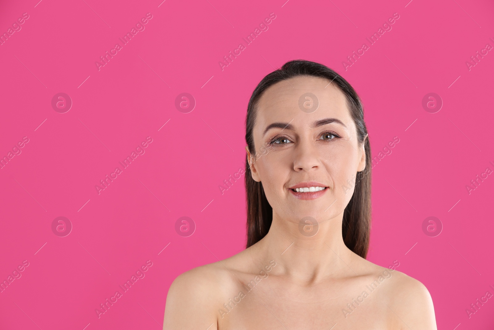 Photo of Portrait of beautiful mature woman on pink background. Space for text