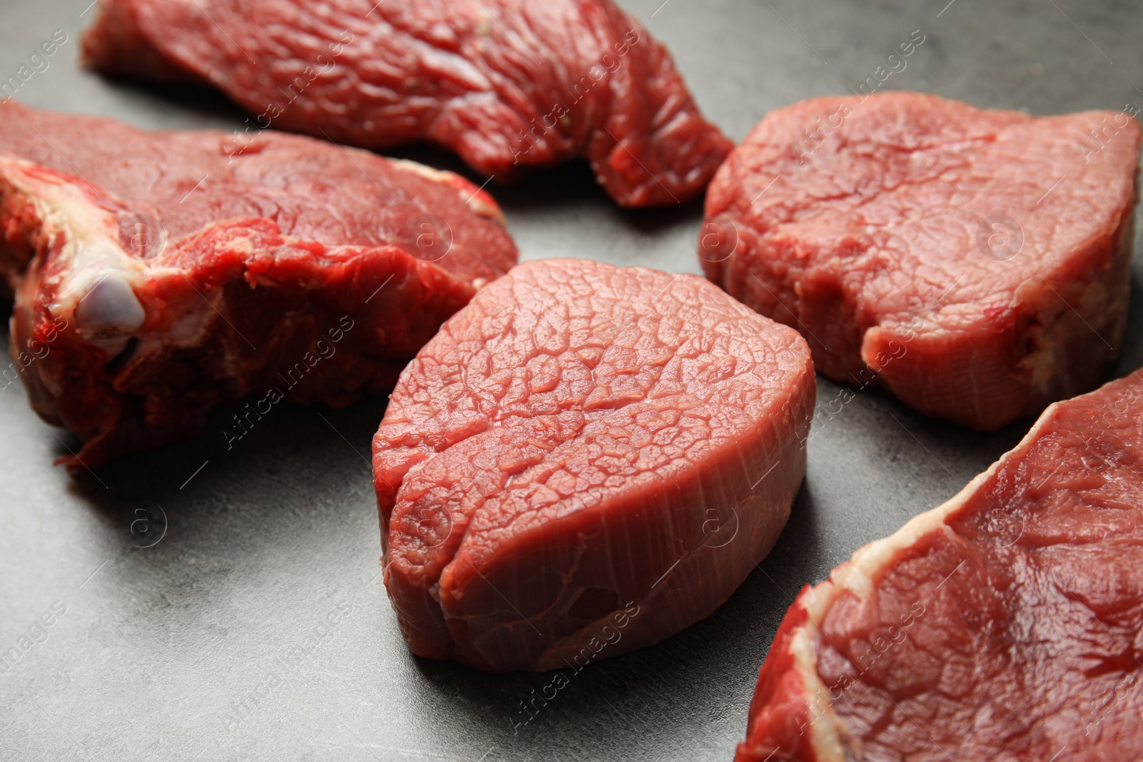 Photo of Fresh raw beef cuts on grey table, closeup