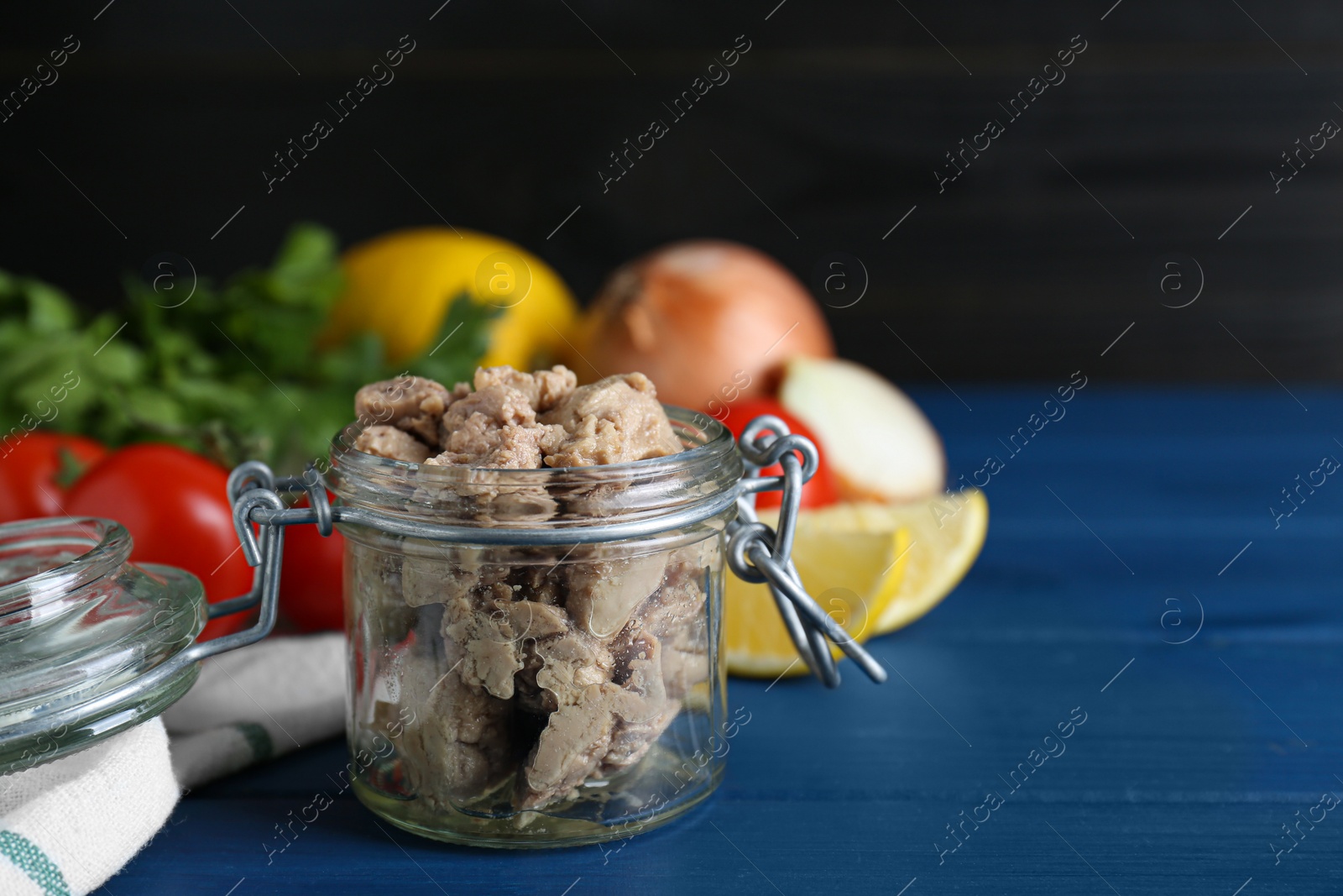 Photo of Glass jar of tasty cod liver on blue wooden table. Space for text