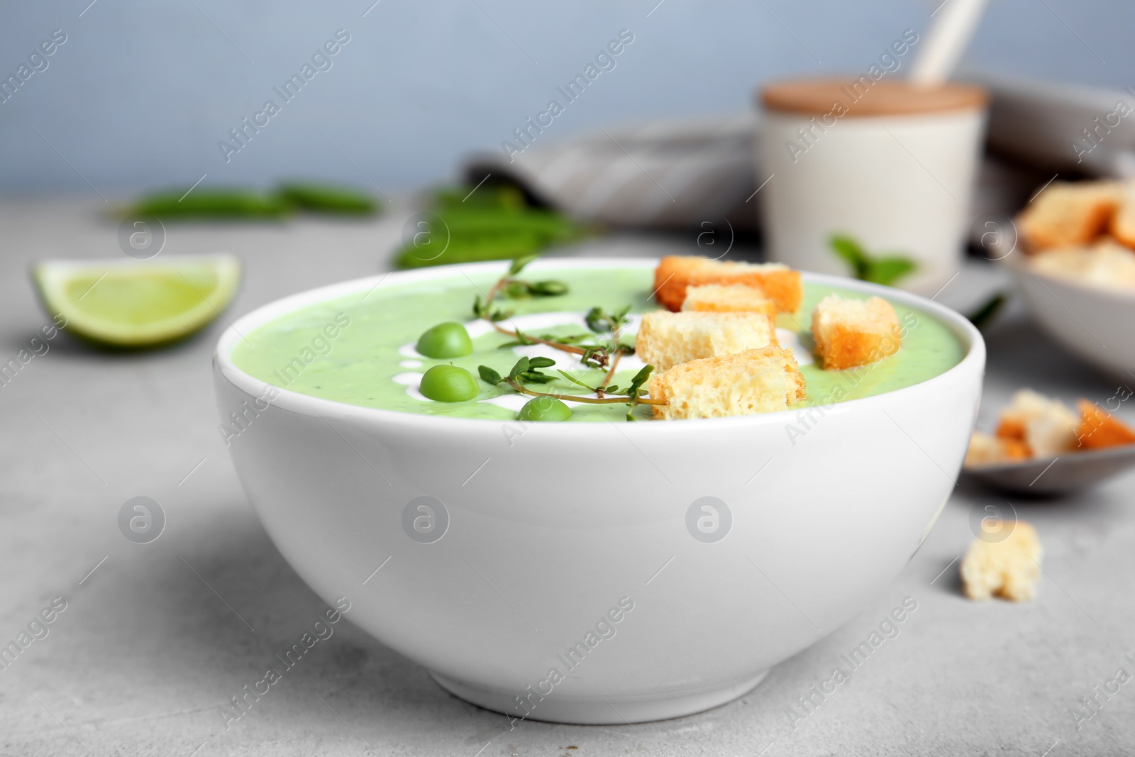 Photo of Green pea soup with croutons in bowl on table