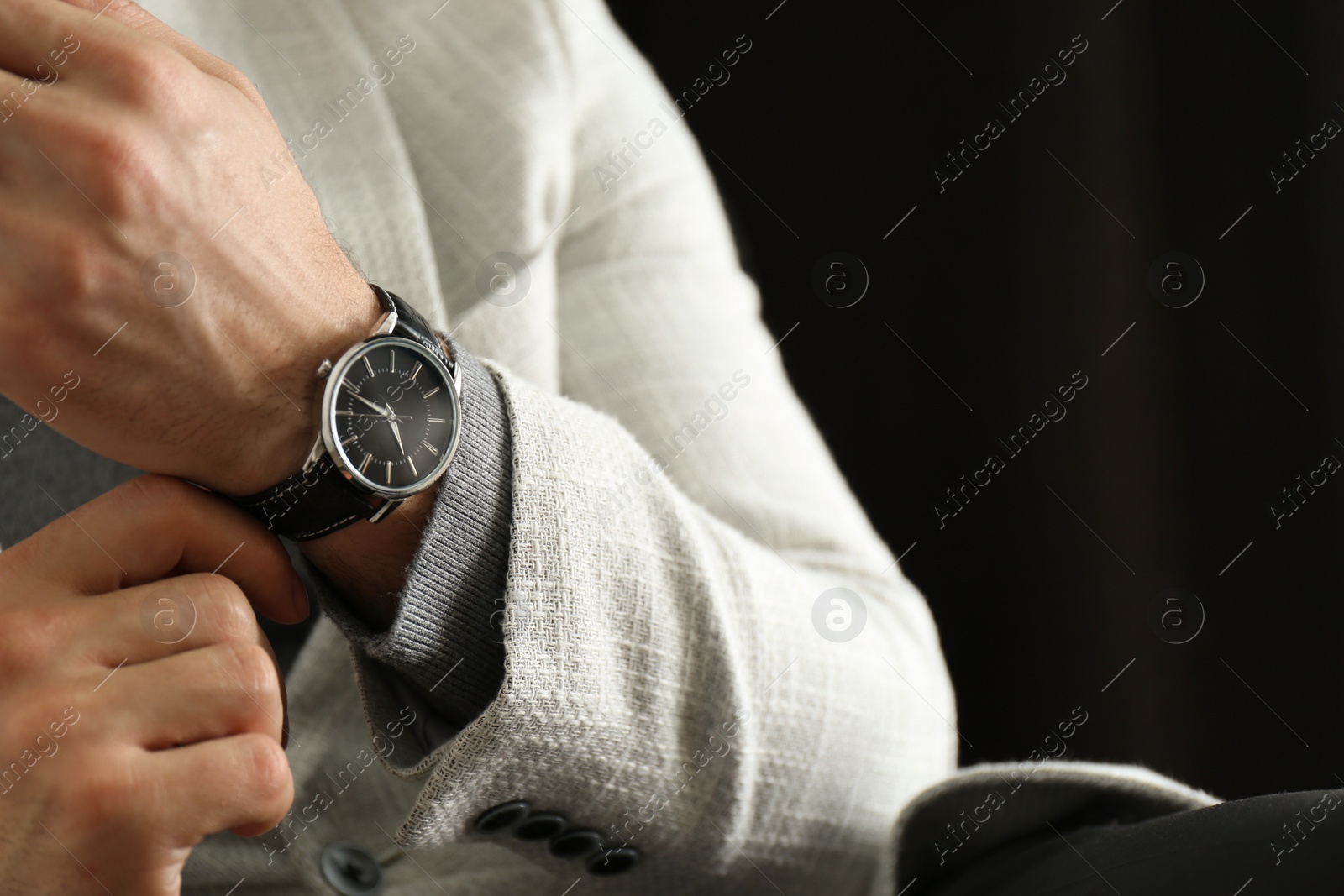 Photo of Businessman with luxury wrist watch on black background, closeup