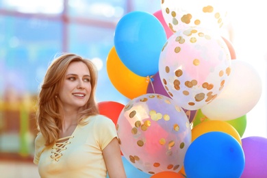 Photo of Young woman with colorful balloons outdoors on sunny day