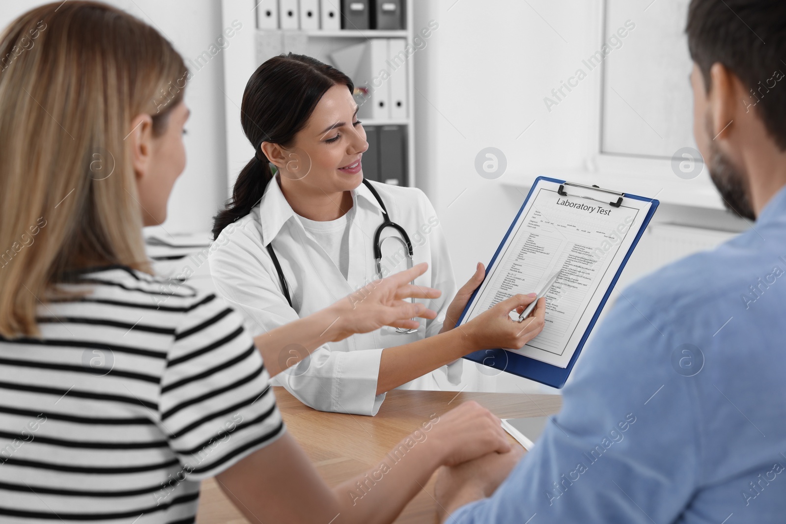 Photo of Couple having appointment with fertility doctor in clinic. Patient consultation