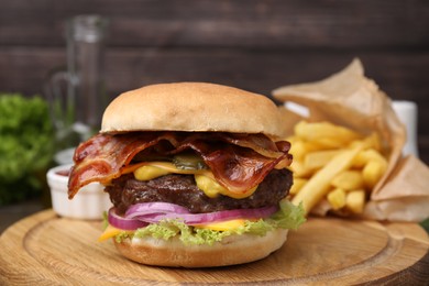 Photo of Tasty burger with bacon, vegetables and patty served with french fries on wooden board, closeup