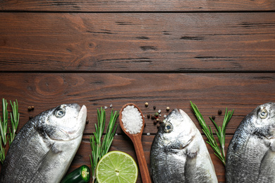 Flat lay composition with raw dorada fish on wooden table, space for text