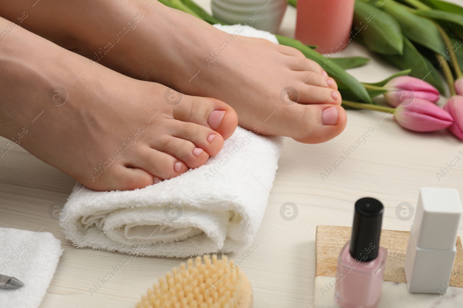 Photo of Woman with neat toenails after pedicure procedure on white wooden floor, closeup