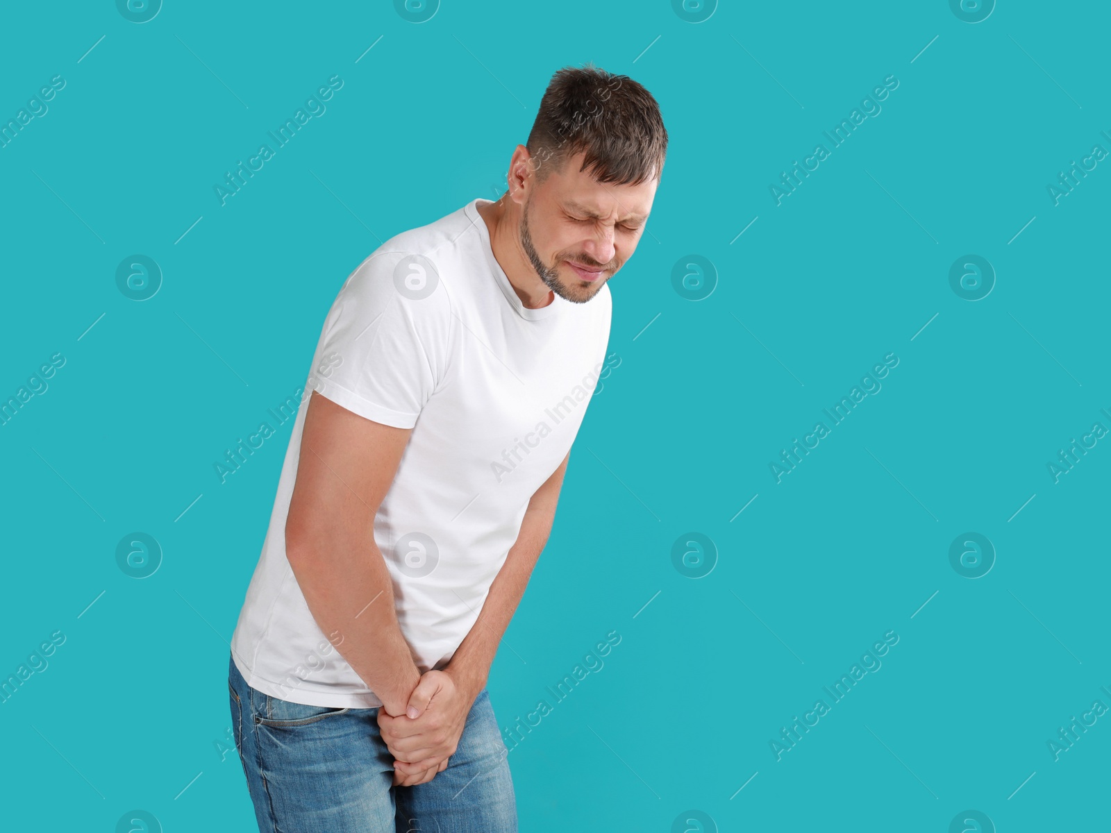 Photo of Man suffering from pain on turquoise background. Urology problems