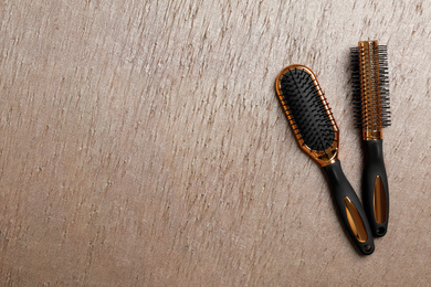 New hair brushes on wooden background, flat lay. Space for text