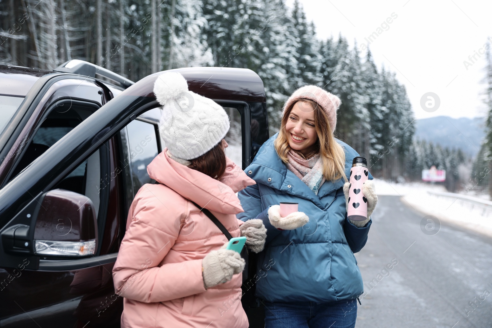 Photo of Friends standing near car on road. Winter vacation