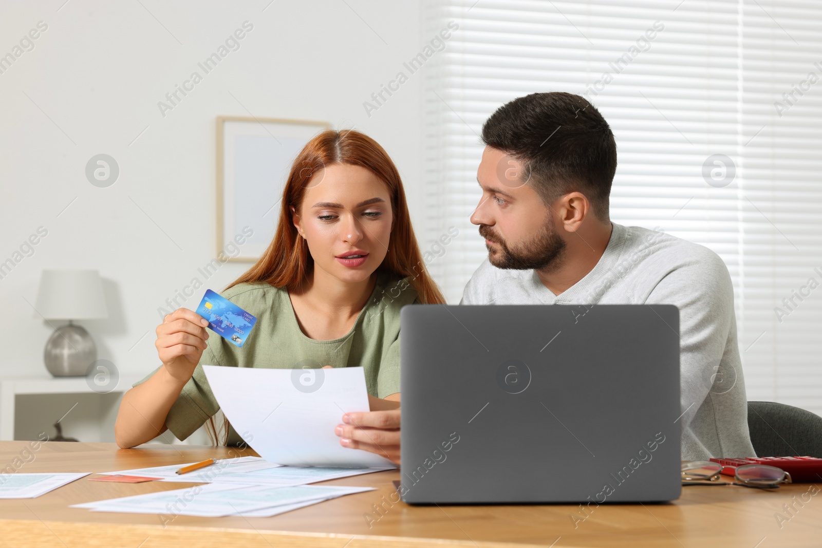 Photo of Couple with credit card using laptop for paying taxes online at home