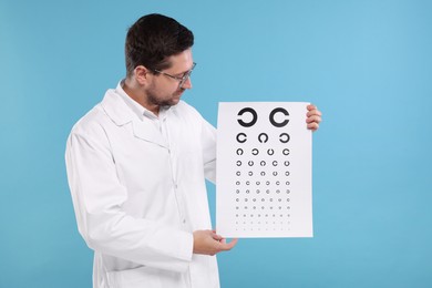 Photo of Ophthalmologist with vision test chart on light blue background