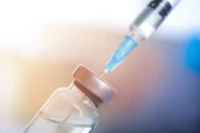 Vial and syringe on blurred background. Vaccination and immunization