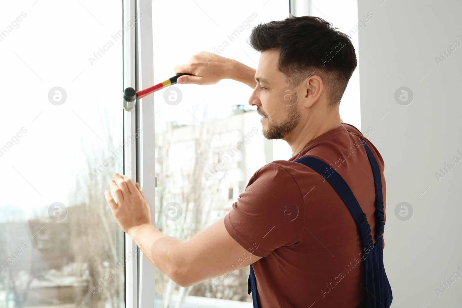 Photo of Professional construction worker installing plastic window indoors